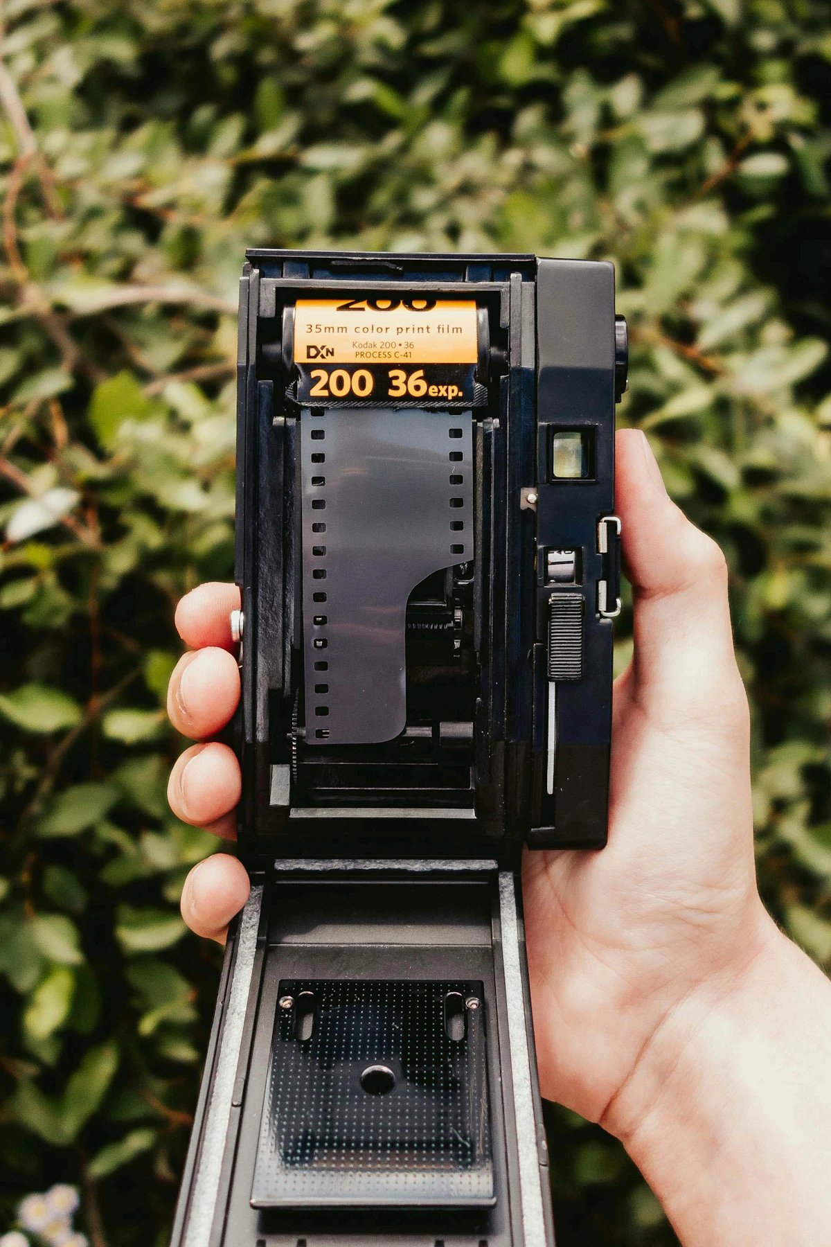 Hand holding a vintage 35mm camera with film exposed