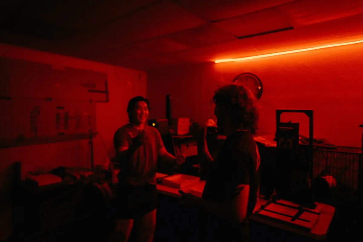 Interior de un laboratorio de revelado fotográfico con equipo y negativos colgados