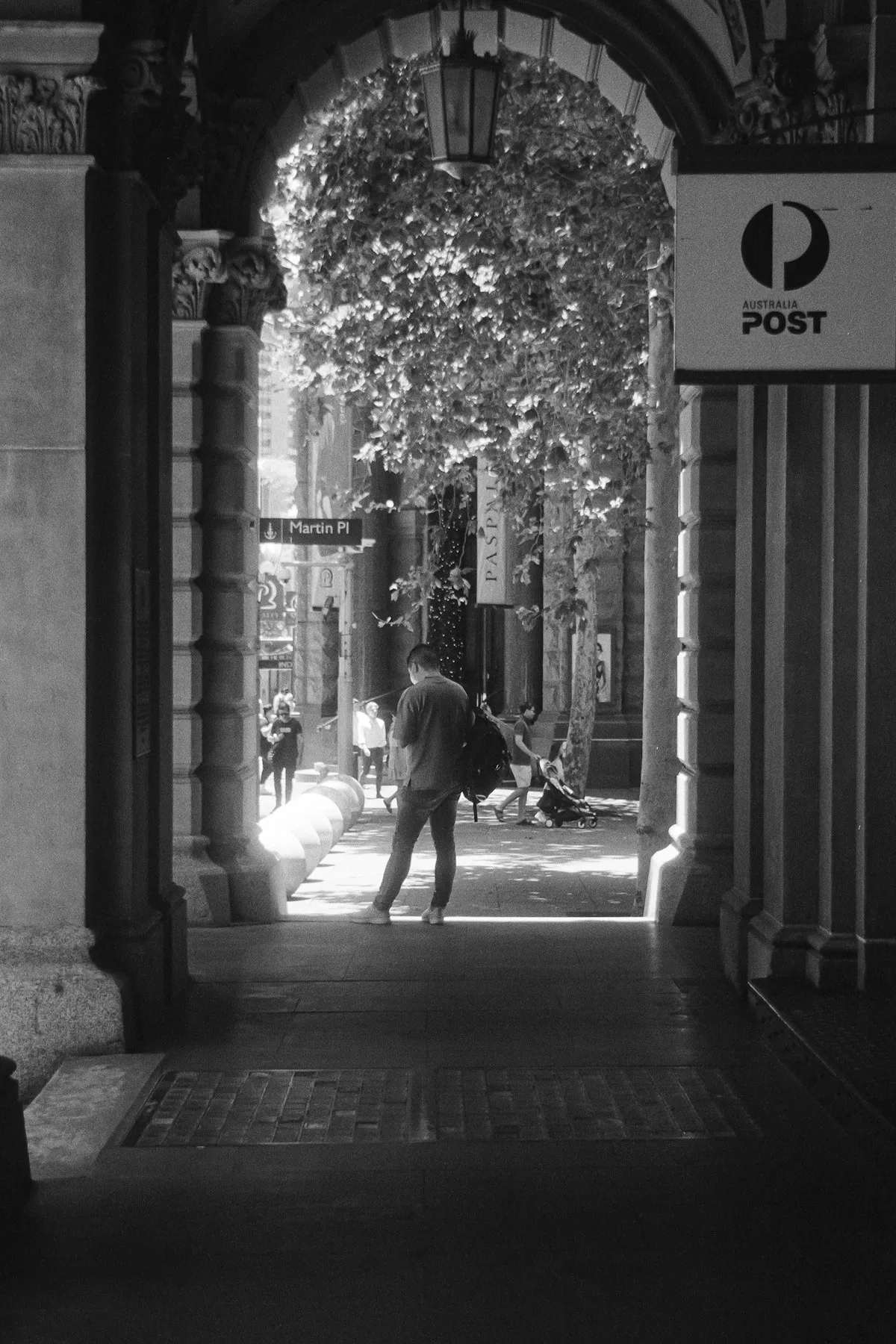 Black and white street scene captured on film showing pedestrians and urban architecture