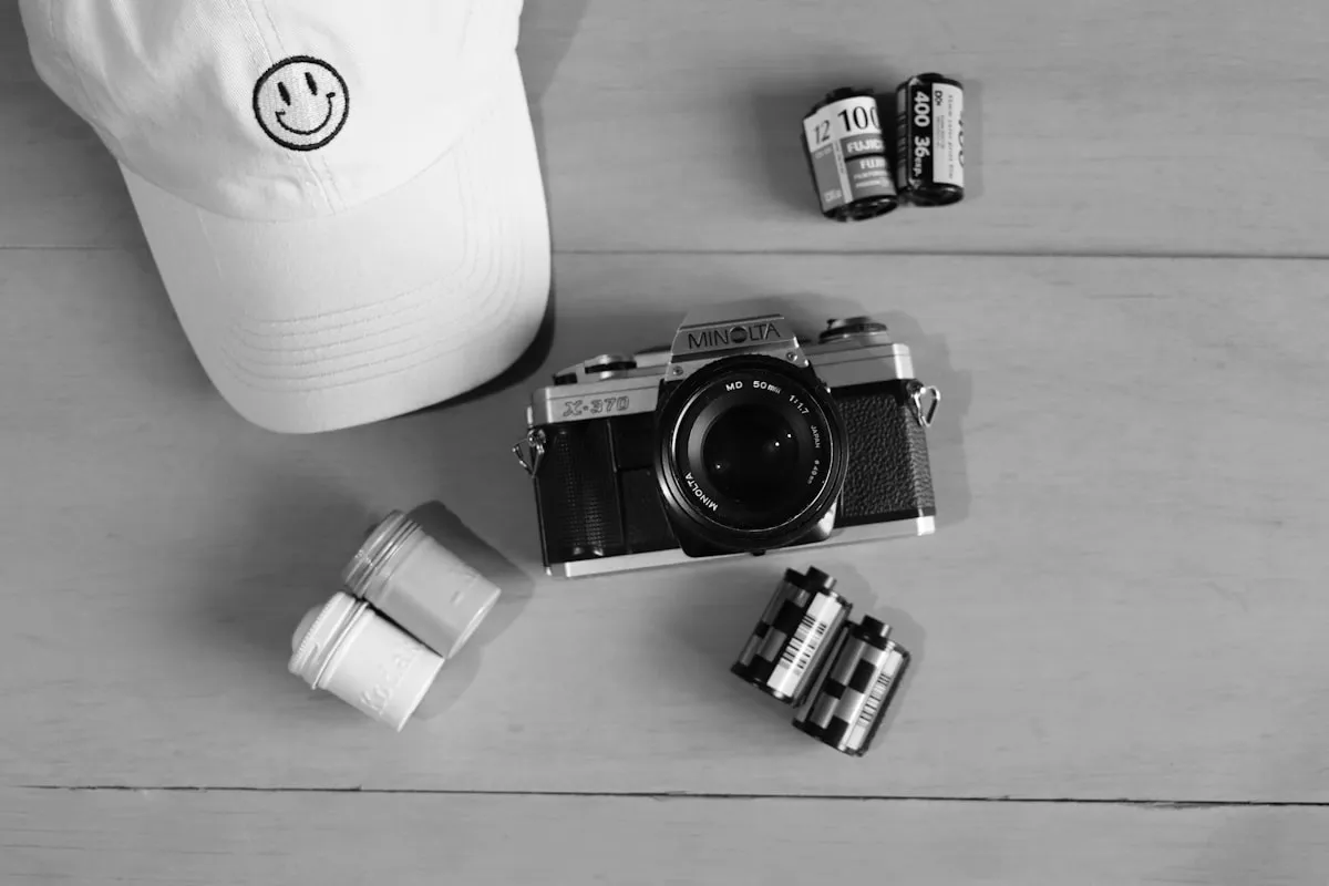 Flat lay of a film camera, hat, and analog photography gear